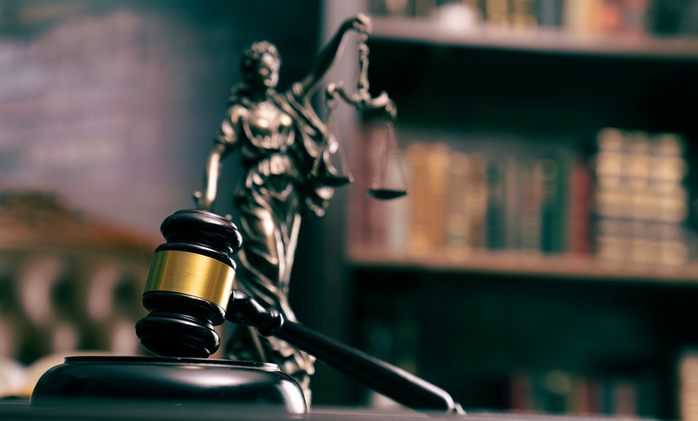 selected focus on gavel with a lady justice statue and bookshelf in the background